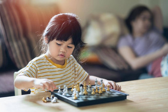 亚洲婴儿玩国际象棋生活房间首页聪明的孩子时尚孩子们天才孩子聪明的游戏棋盘婴儿活动概念