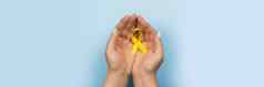 黄色的黄金丝带手女孩蓝色的背景孩子们癌症概念意识月童年癌症一天2月网络横幅