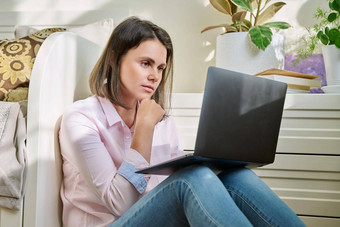 伤心年轻的女人移动PC屏幕坐着地板上首页