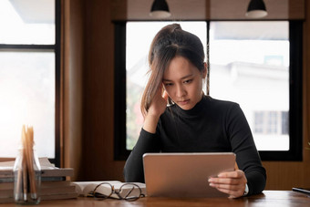 累了年轻的亚洲女人办公室工作数字平板电脑桌子上工作疲惫女商人头疼