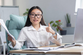 年轻的金融女人<strong>微</strong>笑相机亚洲业务女人相机<strong>微</strong>笑持有好金融报告手显示拇指