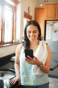 快乐混合比赛女人微笑聪明的电话首页女人阅读文本消息聊天社会媒体忙家务厨房
