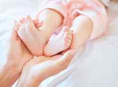 妈妈。持有婴儿脚特写镜头小新生儿婴儿脚举行父小婴儿脚趾婴儿说谎床上女人持有脚婴儿女孩无辜的婴儿举行妈妈。