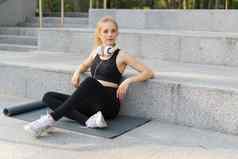 体育运动健身年轻的成人高加索人女人坐着锻炼席混凝土地板上休息早....锻炼户外夏天公园