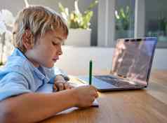 年轻的自主学习男孩坐着移动PC研究高加索人孩子写作学习远程由于科维德流感大流行孩子研究在线类技术视频调用