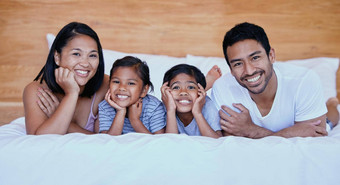 快乐家庭床上肖像年轻的拉美裔家庭床上年轻的混合比赛家庭父母成键女儿首页姐妹放松妈妈。父亲