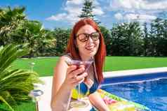 年轻的女人比基尼太阳镜快乐微笑相机坐着边缘池享受喝年轻的女孩夏天假期夏天概念旅行