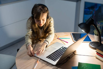 连接<strong>好孩子</strong>女孩坐安慰舒适的表格桌子上研究远程移动PC在线老师沟通聊天耳机房子在室内