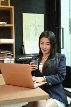 亚洲女经理工作移动PC电脑移动电话办公室桌子上