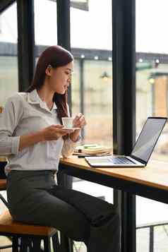 肖像女企业家喝热咖啡阅读电子邮件移动PC电脑