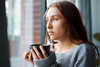 热杯茶安抚灵魂拍摄不开心年轻的女人喝茶窗口