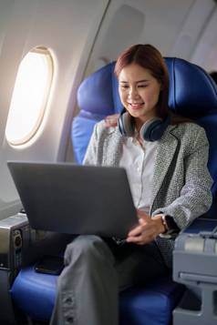 肖像成功的亚洲业务女人女企业家正式的西装飞机坐在业务类座位电脑移动PC飞行