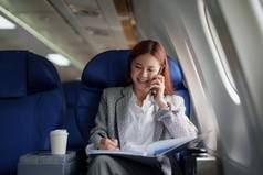 肖像成功的亚洲业务女人女企业家正式的西装飞机坐在业务类座位智能手机文档工作飞行