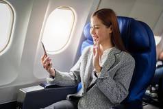 肖像成功的亚洲女商人女企业家正式的西装飞机坐在业务类的座位智能手机飞行