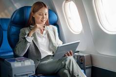 肖像成功的亚洲女商人女企业家正式的西装飞机坐在业务类的座位平板电脑电脑飞行