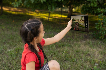 孩子女孩玩数字平板电脑花园在线远程教育概念