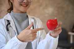 微笑年轻的女医生持有红色的心形状手医疗保健医疗概念