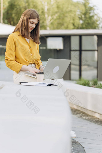 年轻的欧洲业务女人<strong>自由职业者</strong>坐着板凳上工作移动PC城市公园现代城市街背景忙工人<strong>自由职业者</strong>工作现代科技笔记本设备