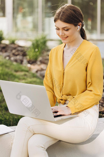 年轻的女人穿耳机坐着前面开放移动PC电脑之前肖像有吸引力的女人移动PC共同办公空间研究远程工作学习自由