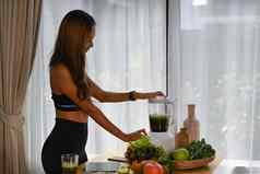 健康的女人使绿色蔬菜排毒奶昔搅拌机厨房健康的生活方式概念