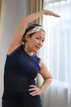 快乐中间岁的女人锻炼例程锻炼在室内伸展运动肌肉健康生活方式概念