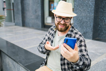 有胡子的男人。视频调用智能手机户外视频连接技术概念