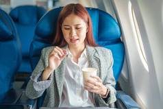 肖像成功的亚洲女商人企业家正式的西装飞机业务类采取运动病药片飞行