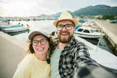 年轻的夫妇采取肖像笑构成关闭相机智能手机在户外夏天港口玛丽娜船游艇