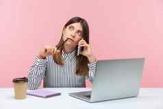 情感年轻的女人坐着工作办公室粉红色的背景