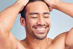 微笑肌肉发达的亚洲男人。洗澡工作室洗头发蓝色的背景适合强大的混合比赛男人。站倒水拉美裔运动员享受热淋浴