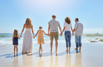 后视图家庭持有手有趣的海滩假期阳光明媚的一天亲戚享受夏天阳光成键支出质量时间走感觉海洋水