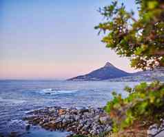 海洋视图浅岩石海岸线狮子头表格山国家公园角小镇南非洲背景安静的平静海滩日落美丽的夏天晚上