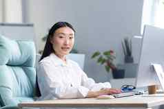 美丽的亚洲女人作品电脑办公室相机微笑业务女人白色衬衫打字键盘