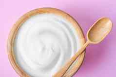 希腊酸奶木碗干大麦粉红色的背景