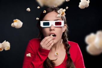 激动人心的经验拍摄年轻的女人穿眼镜吃爆米花工作室背景