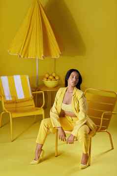 阳光工作室拍摄年轻的女人穿着时尚的黄色的衣服黄色的背景