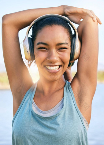 肖像快乐女人warmup延伸耳机音乐锻炼微笑女运动员准备身体肌肉培训运行有氧运动锻炼