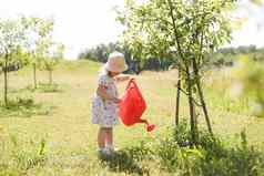 可爱的婴儿女孩年衣服浇水植物浇水花园孩子们有趣的园艺明亮的阳光明媚的一天户外活动孩子们