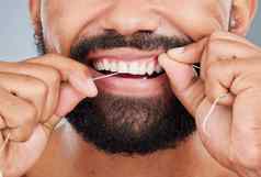 给牙齿额外的护理工作室拍摄认不出来男人。牙科牙线灰色背景