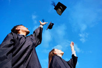 使前低角拍摄年轻的学生扔帽子空气毕业一天