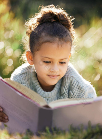 女孩阅读书放松公园花园混合比赛孩子学习教育说谎草自然有趣的