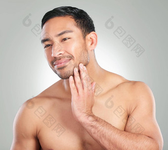 皮肤护理工作室拍摄英俊的年轻的男人。触碰脸灰色背景