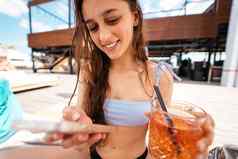 年轻的女人手机聊天在线游泳池
