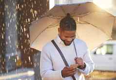 好新闻倒年轻的商人手机持有伞多雨的一天城市
