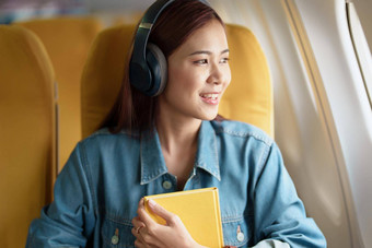 有吸引力的肖像亚洲女人坐着窗口座位<strong>经济类</strong>阅读书听仪器音乐飞机飞行旅行概念假期放松