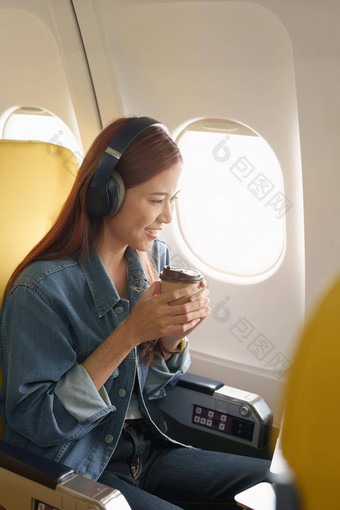有吸引力的肖像亚洲女人坐着窗口座位<strong>经济类</strong>听音乐飞行飞机旅行概念假期放松