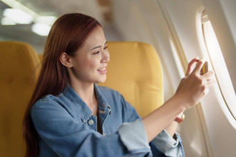 有趣的肖像亚洲女人坐着窗口经济类移动电话照片天空飞机概念旅行假期放松