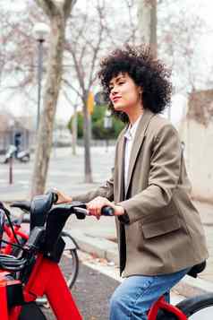 年轻的拉丁女人游乐设施电租赁自行车