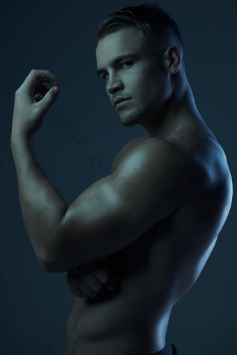 图片强度男子气概工作室肖像肌肉发达的年轻的男人。摆姿势赤膊上阵黑暗背景