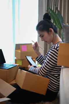 年轻的亚洲女人检查在线订单聪明的电话包装盒子航运